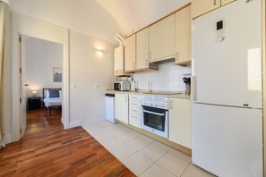 Eine moderne Küche mit weißen Schränken, einem Einbauofen, einer Mikrowelle und einem Kühlschrank.