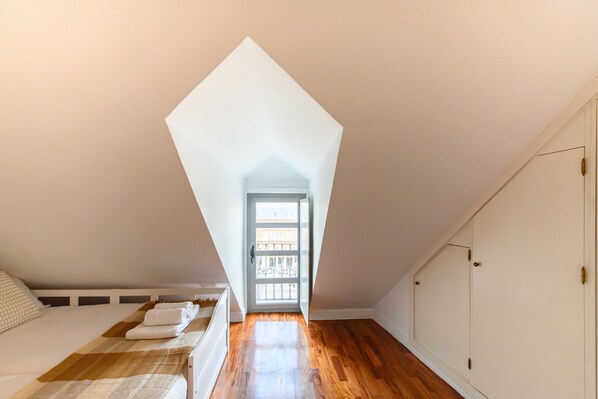 A bedroom with a sloped ceiling, a bed with a checkered blanket, and a wooden floor. - M Tol241 Espectacular Piso en la Plaza Mayor (Madrid)