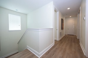 A hallway with wooden flooring, white walls, and a window with blinds. - 5BR Near Disney with Private Pool at Encore Resort (Kissimmee)