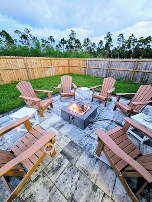 A patio with Adirondack chairs, a square table, and a fire pit. - Pet friendly - 10/20 available -Walk to the beach -3 bdrm + backyard & firepit (Port St. Joe)