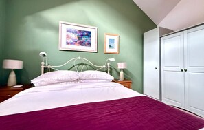 A bedroom with a bed, two bedside lamps, a wardrobe, and two framed pictures on the wall. - Charming Barn Conversion | Dog Friendly | Sleeps 4 (Cornwall)
