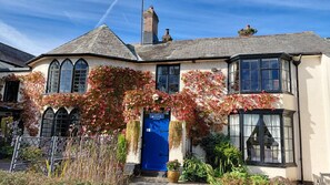A traditional house with a blue door, ivy-covered walls, and a chimney. - Luxury Apartment for Couples | Dog Friendly | Near Dartmoor (Cornwall)
