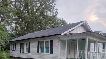 Een gelijkvloers huis met een veranda, voortuin en oprit.