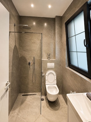 A modern bathroom with a glass-enclosed shower, a toilet, and a bathtub. - ODA Central Stay (Elbasan)