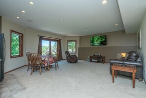 A spacious living room with a dining area, a leather sofa, a flat-screen TV, and a fireplace.