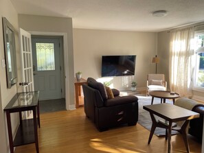 A living room with a sofa, a TV, a coffee table, and a chair. - 3BR Main-Floor Home | Private Yard & Parking | Near CHEO & Downtown (Ottawa)