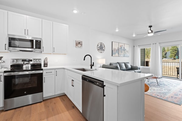 A modern kitchen with white cabinetry, stainless steel appliances, and a central island with a sink. - Modern Brightwood Rental Steps from Keystone Village Dining & Slopes (Keystone)