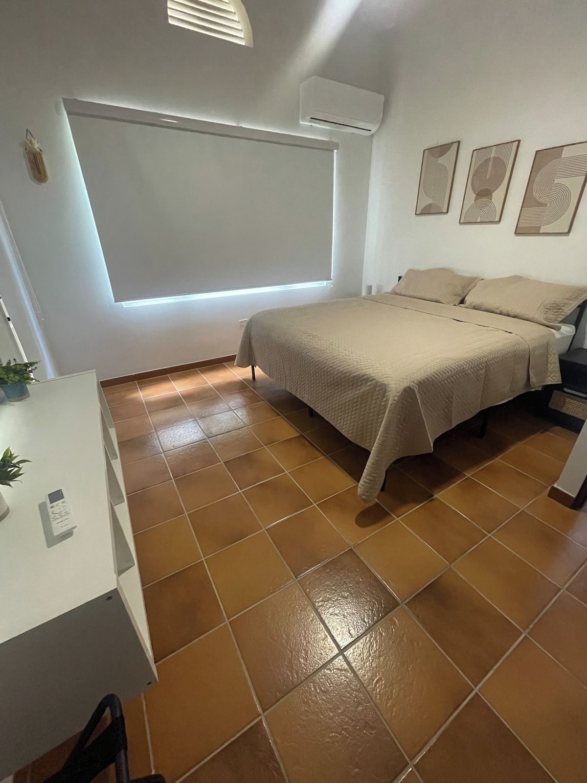 Um quarto com cama, escrivaninha e janela.
