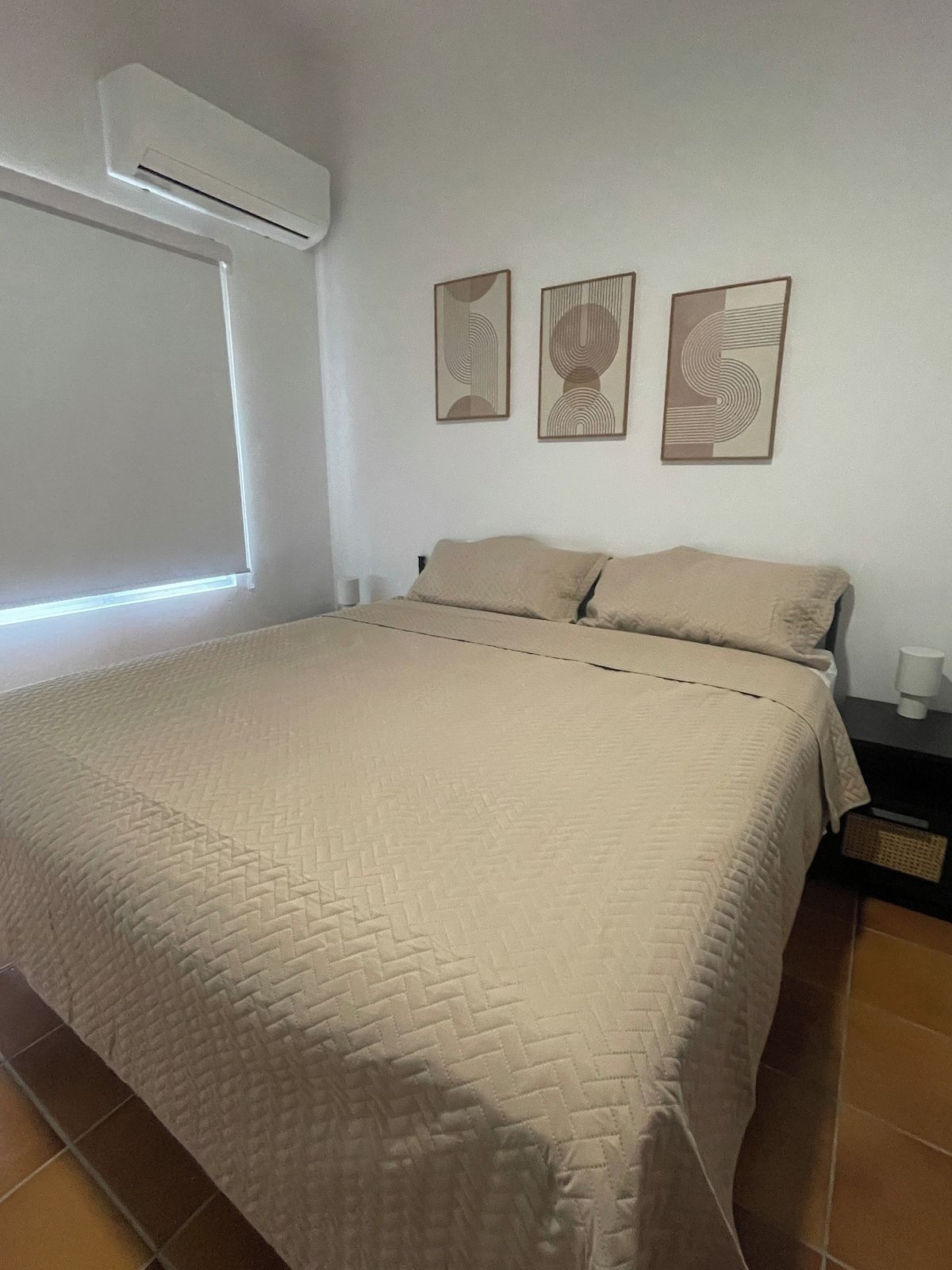 Un dormitorio con una cama, una mesita de noche y una obra de arte en la pared.