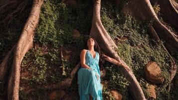A person sitting on a rock surrounded by tree roots and greenery.