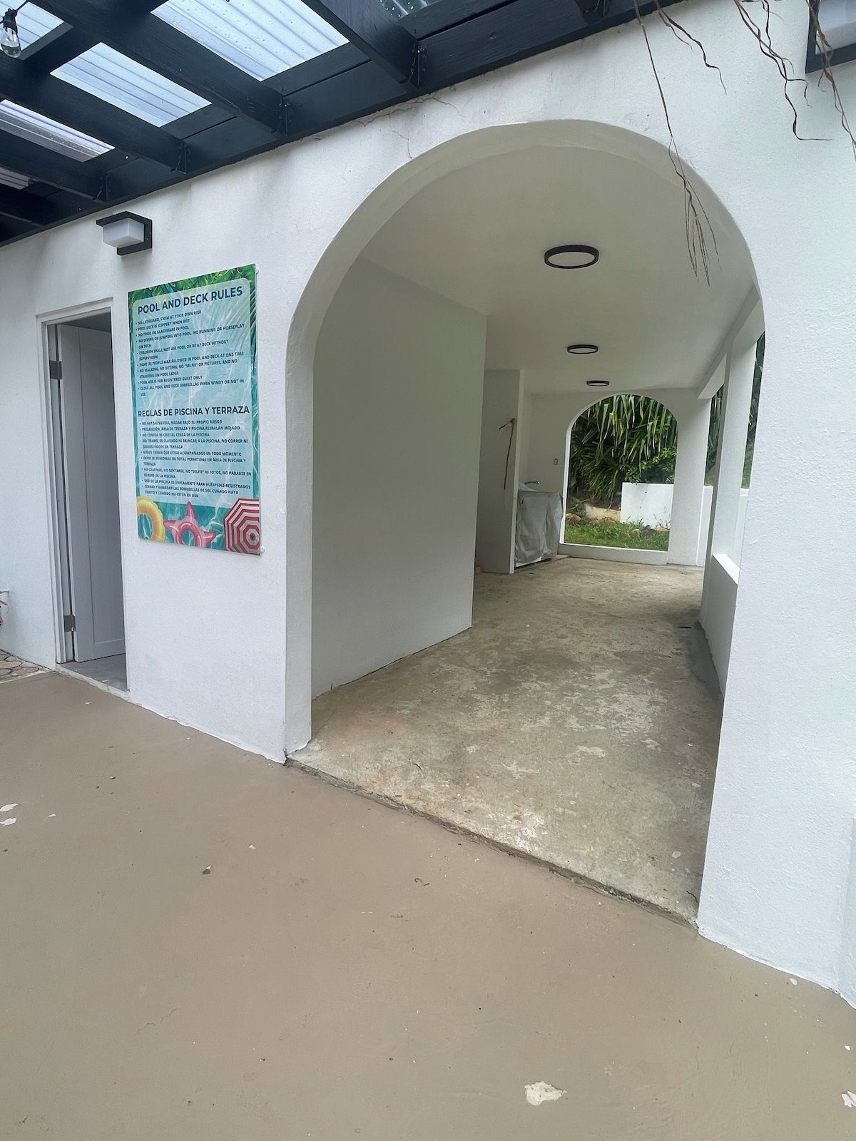 Uma galeria coberta que dá acesso a uma área de piscina, com uma placa que explica as regras da piscina e do deck.