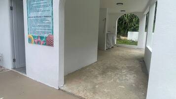 A covered walkway leading to a pool area with a sign detailing pool and deck rules.