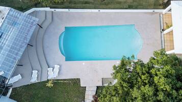 Una piscina rectangular con un solárium alrededor y sillas de descanso.