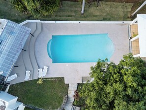 A rectangular swimming pool with a surrounding deck and lounge chairs.