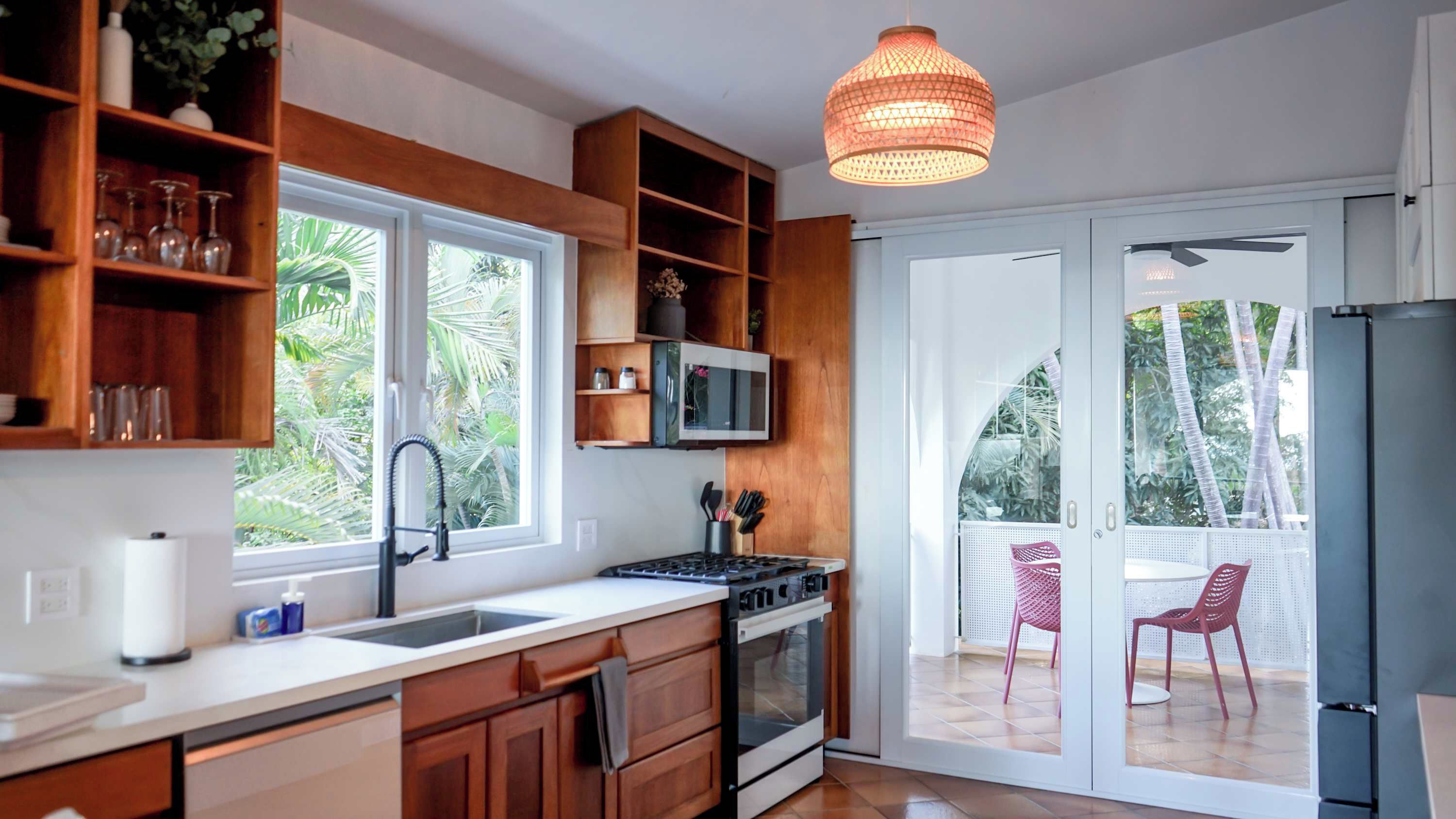 Une cuisine moderne avec des meubles en bois, un évier en acier inoxydable et une grande fenêtre.