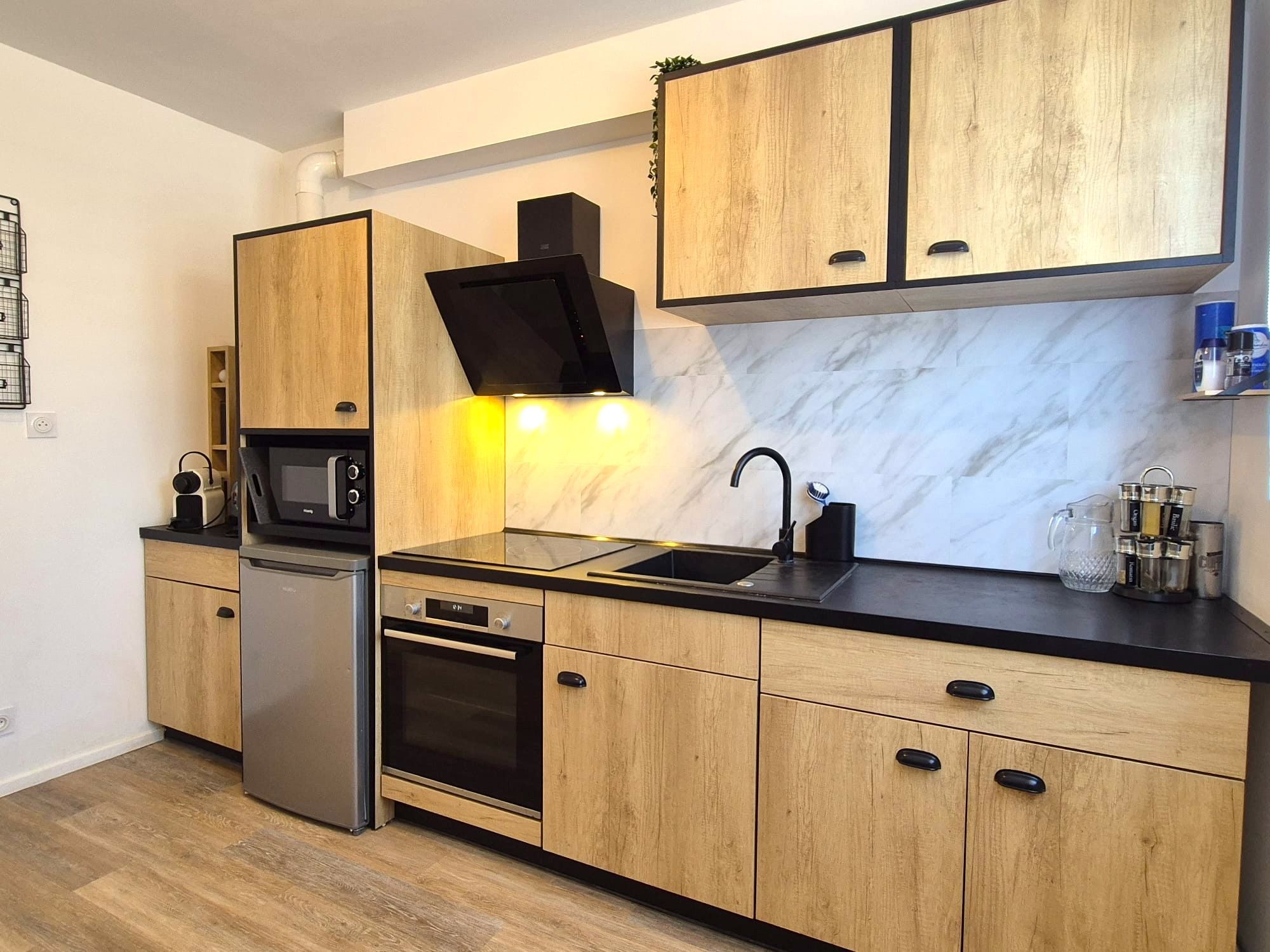 Een moderne keuken met houten kastjes, een inbouwoven, een magnetron en een spoelbak.