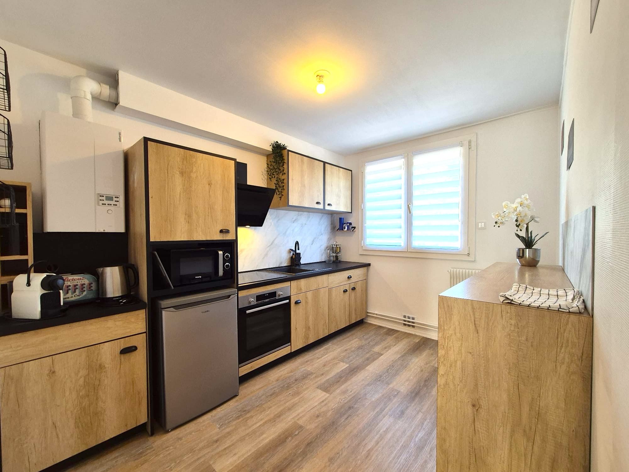 A modern kitchen with wooden cabinets, a built-in microwave, and a stainless steel refrigerator.