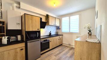A modern kitchen with wooden cabinets, a built-in microwave, and a stainless steel refrigerator.