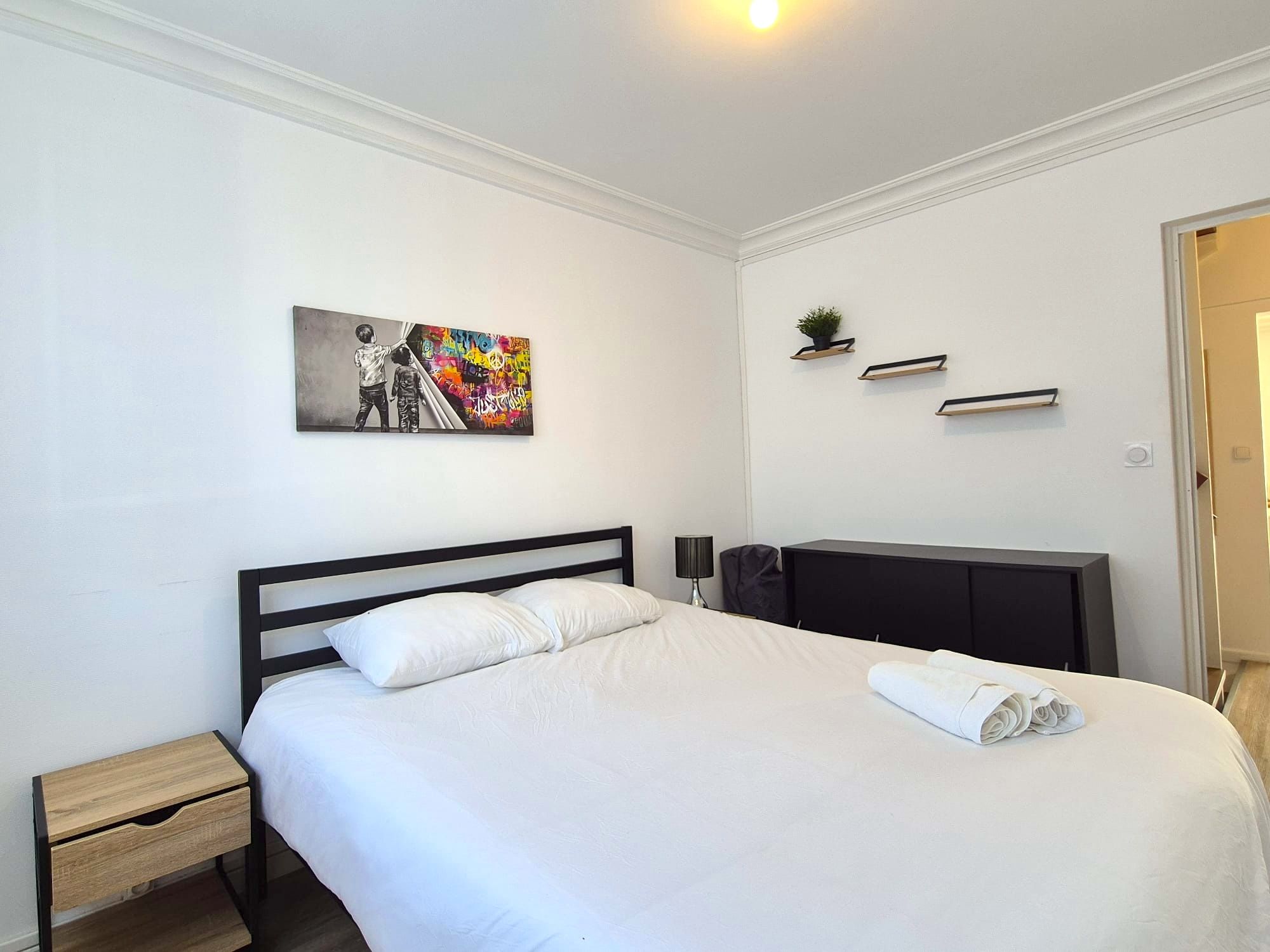 Une chambre d’hôtel avec un lit, une table de chevet, une lampe et un tableau au mur.