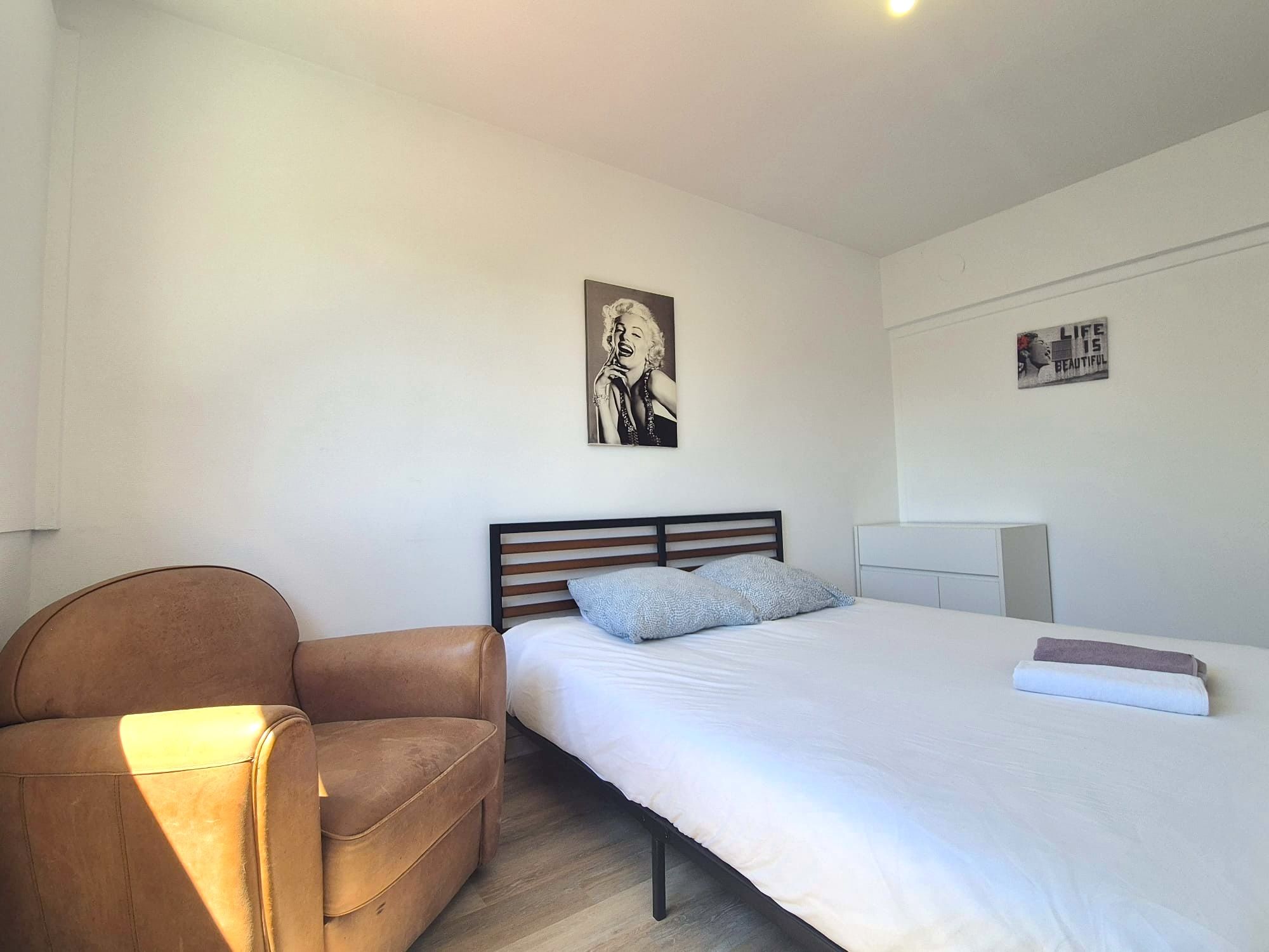 Ein Schlafzimmer mit einem Bett, einem Sessel und einem Wandbild.