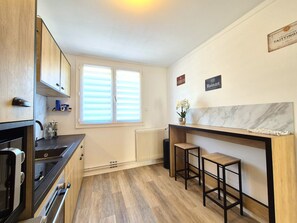 Et moderne køkken med indbygget ovn, et vindue med persienner, en marmor bordplade og et skilt for Ruinart vin.