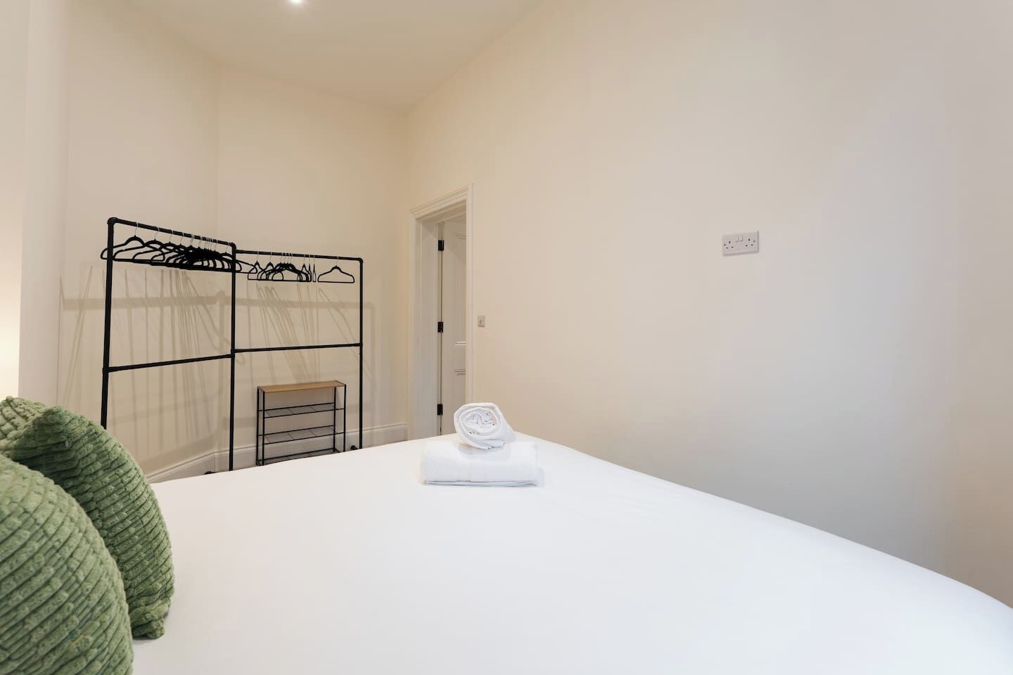 Una habitación de hotel con una cama, un tendedero en la pared y una puerta.
