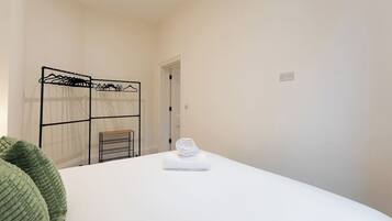 Una habitación de hotel con una cama, un tendedero en la pared y una puerta.