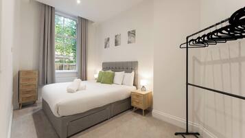 A neatly arranged bedroom with a bed, bedside table, and a wardrobe.
