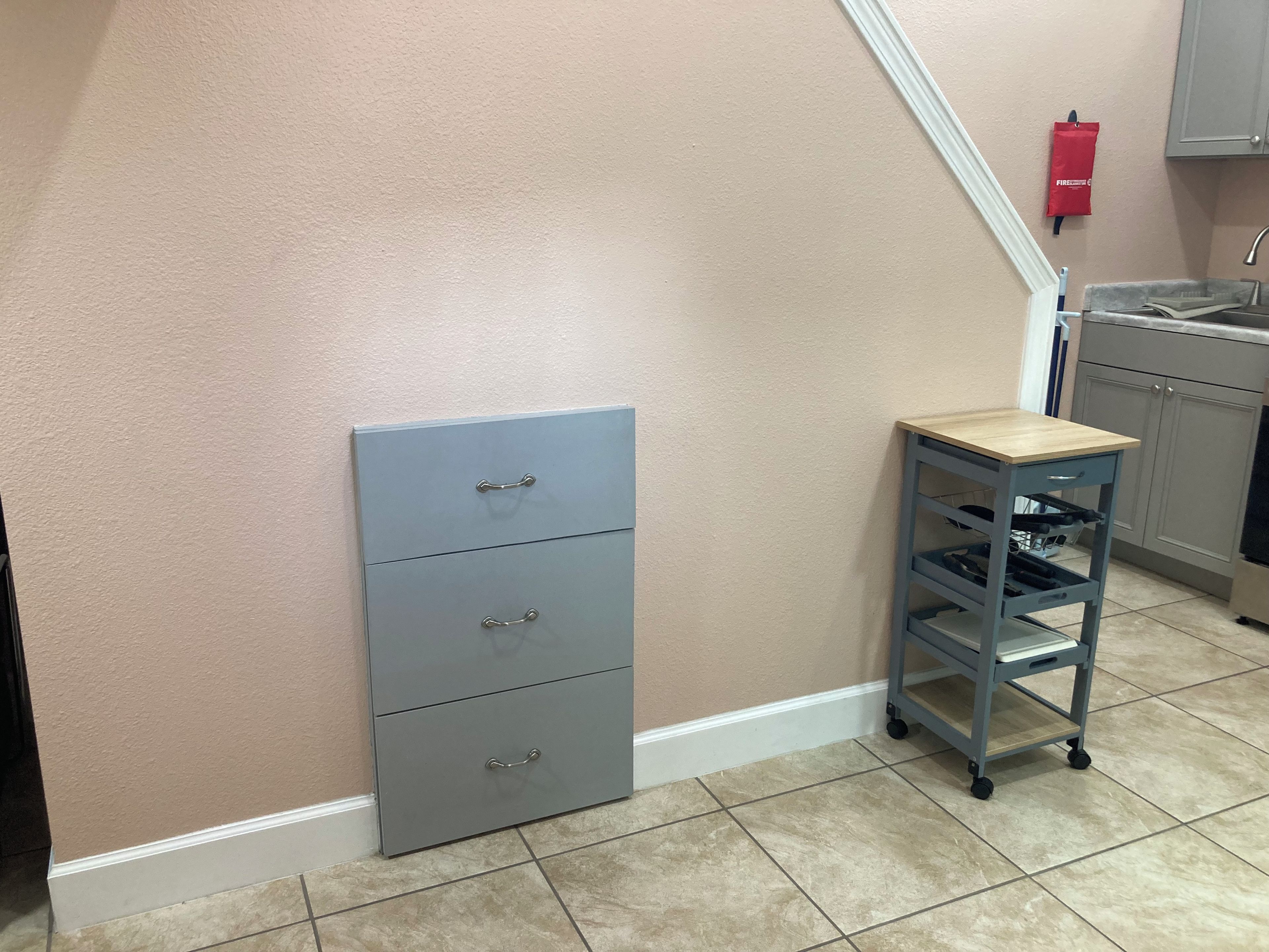 A kitchen with a grey cabinet, a small wooden table, and a tiled floor.