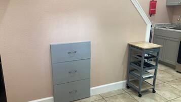 A kitchen with a grey cabinet, a small wooden table, and a tiled floor.