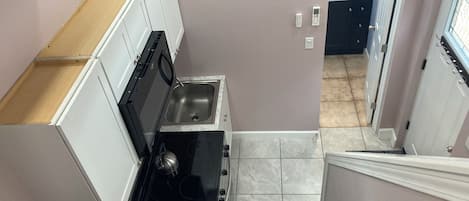A compact kitchen with a built-in oven, a sink, and a stove.