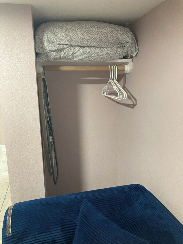 Ein kleines Zimmer mit einem Bett, einem Kleiderhaken und einem Fenster.