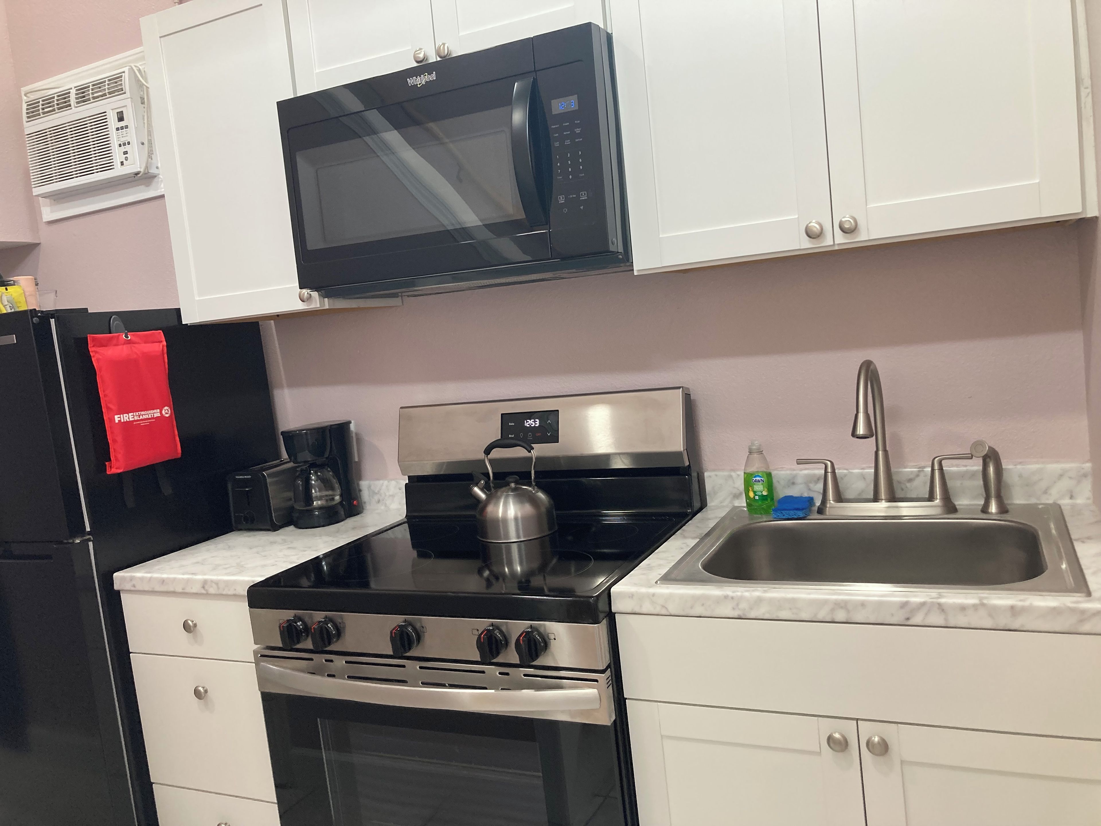 A kitchen with a microwave, stove, sink, and cabinets.