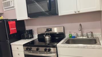 A kitchen with a microwave, stove, sink, and cabinets.