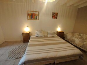 A bedroom with a large bed, two bedside tables with lamps, a rug, and two wall-mounted paintings. - A spacious, cozy, and intimate studio—Olivier—for a stay in the countryside. (Agonges)