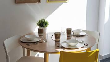 Een ronde eettafel met borden, kommen en mokken, omringd door stoelen.