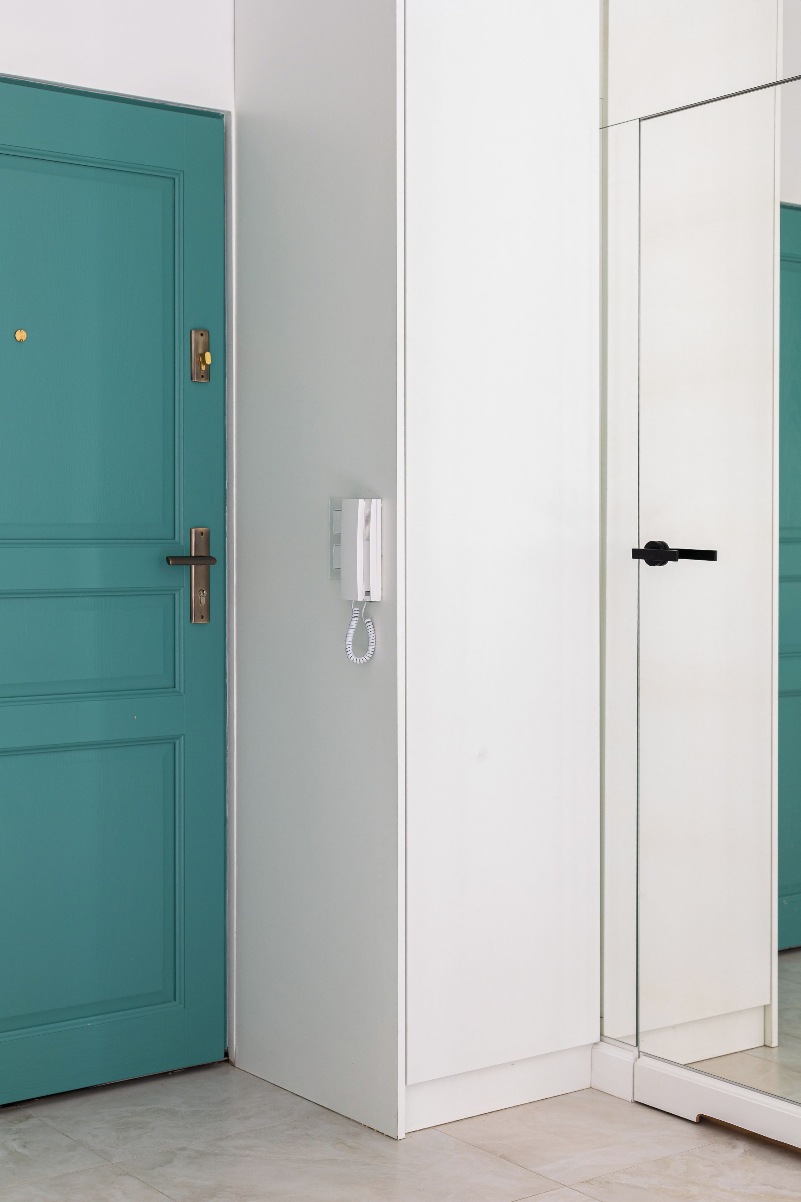 Una puerta color turquesa con manija de latón y una puerta blanca con manija negra.