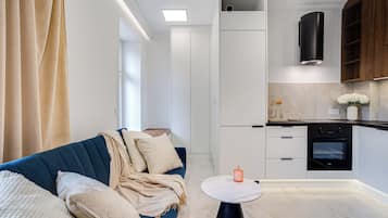 Una cocina moderna con armarios blancos, un horno negro y una pequeña mesa redonda con una vela.