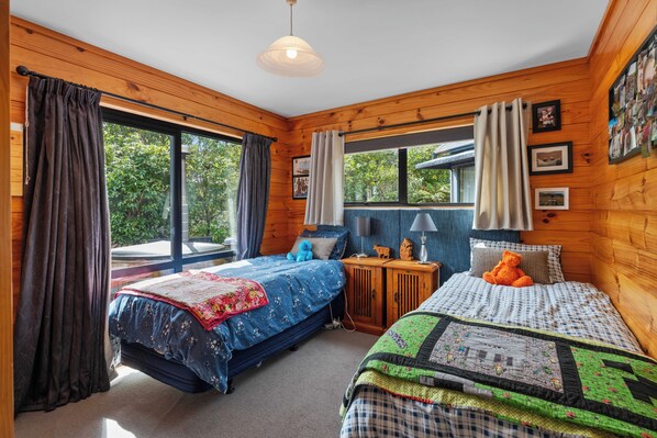 Ein Schlafzimmer mit zwei Betten, Holzwänden, einem Fenster mit Vorhängen und einer Deckenleuchte.