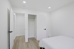 Un dormitorio con cama, armario y puerta que da a otra habitación.