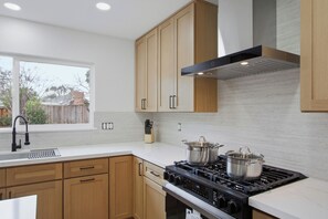 Una cocina moderna con armarios de madera, una estufa de acero inoxidable y una ventana con vistas a un patio trasero.