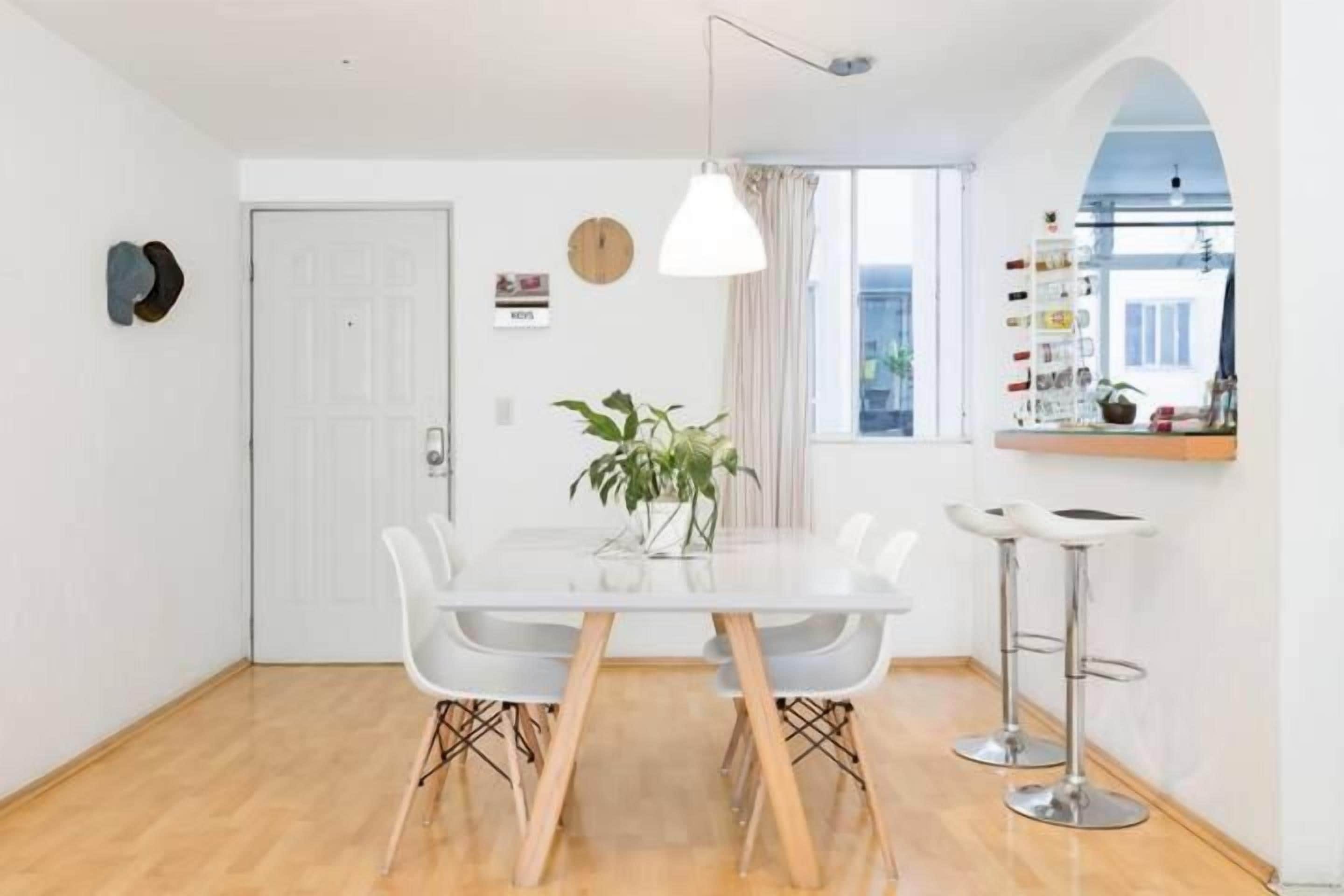 Un comedor con una mesa blanca, sillas y una lámpara colgante.