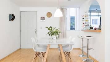 Un comedor con una mesa blanca, sillas y una lámpara colgante.