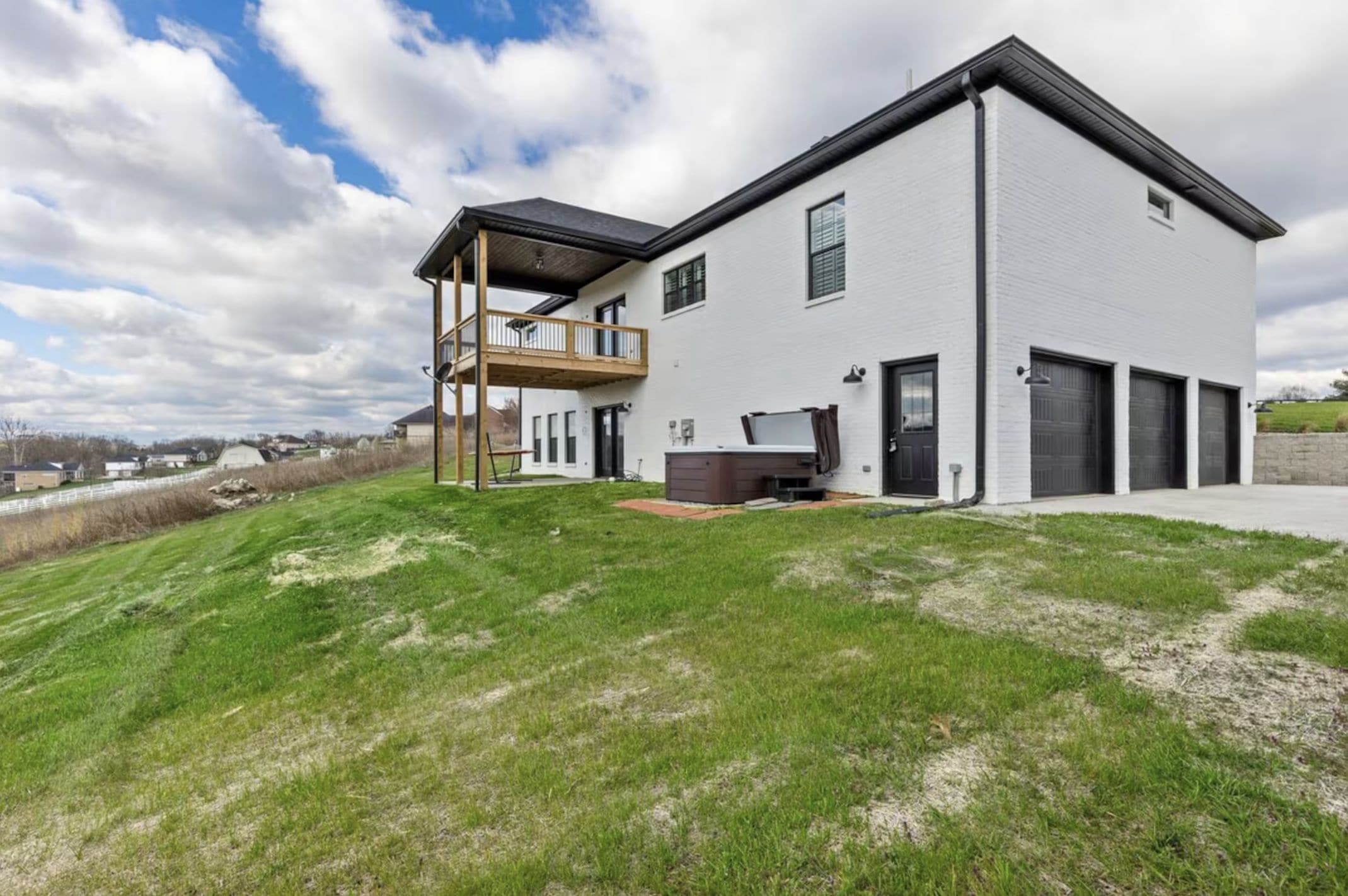 A modern two-story house with a balcony, a garage, and a well-maintained lawn.