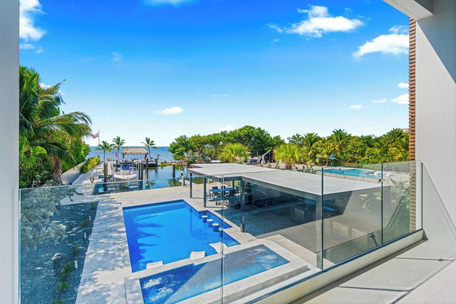 A modern resort with a large infinity pool, a boat dock, and a clear view of the ocean.