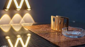 A textured surface with a clear glass ashtray and a metal object with cut-out shapes.