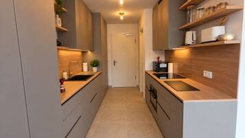 A modern kitchen with a central island, built-in appliances, and wooden cabinetry.
