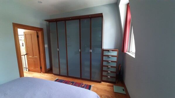 A bedroom with a bed, a wardrobe, a small desk, and a window with curtains. - Modern, Comfortable 1 BR Townhome with Full Kitchen and Office (Toronto)