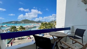 Ein Balkon mit Blick auf eine Marina, ein runder Holztisch, zwei Stühle und ein Geländer.
