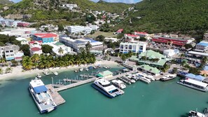 A coastal town with a marina, buildings, and a hilly backdrop. - Beachfront 2BR/2BA on Great Bay · Starlink+Parking (Philipsburg)